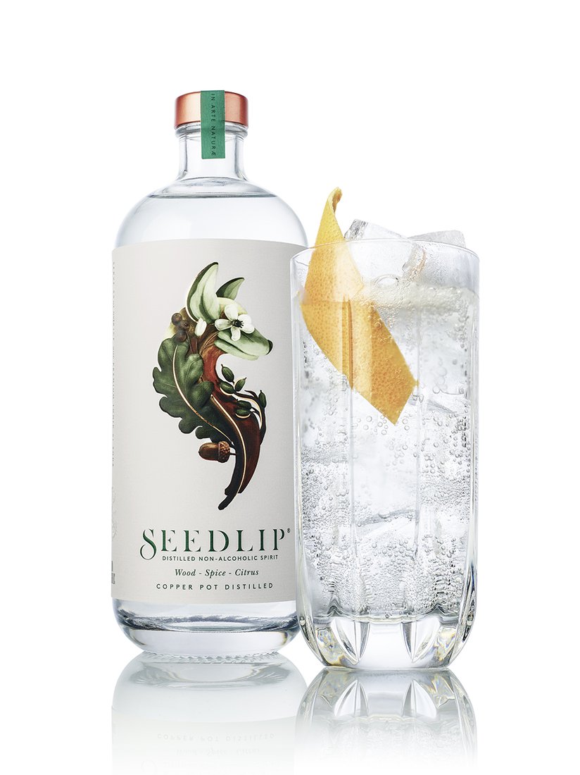 Seedlip is in a tall glass with tonic and a twist, next to a Seedlip bottle. 